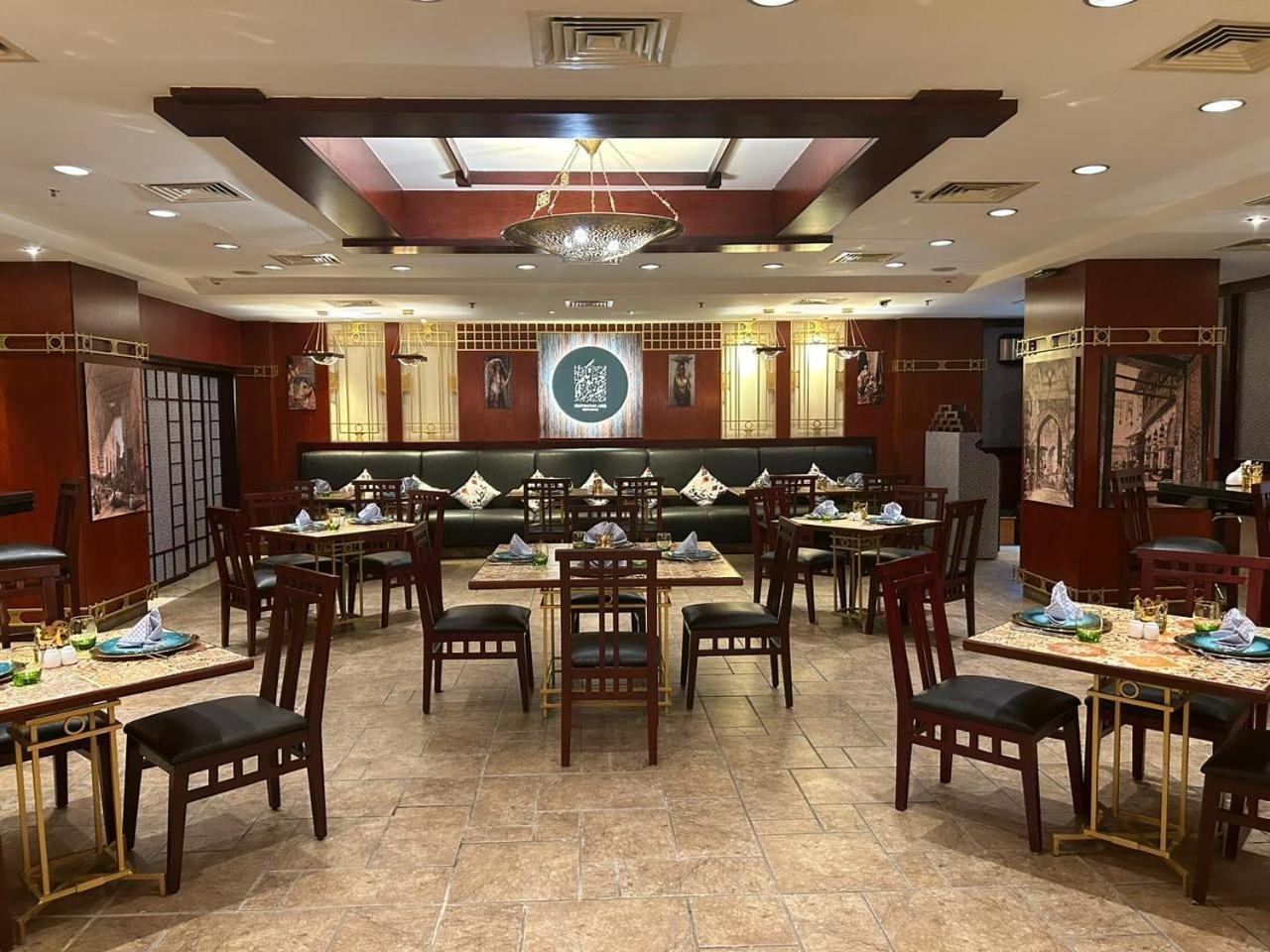 Safir Hotel Cairo Giza Ngoại thất bức ảnh The photo shows the interior of a restaurant. The space features a combination of warm wood tones and elegant decorations. There are several dining tables arranged throughout, each set with plates, cutlery, and decorative napkins. The walls are adorn