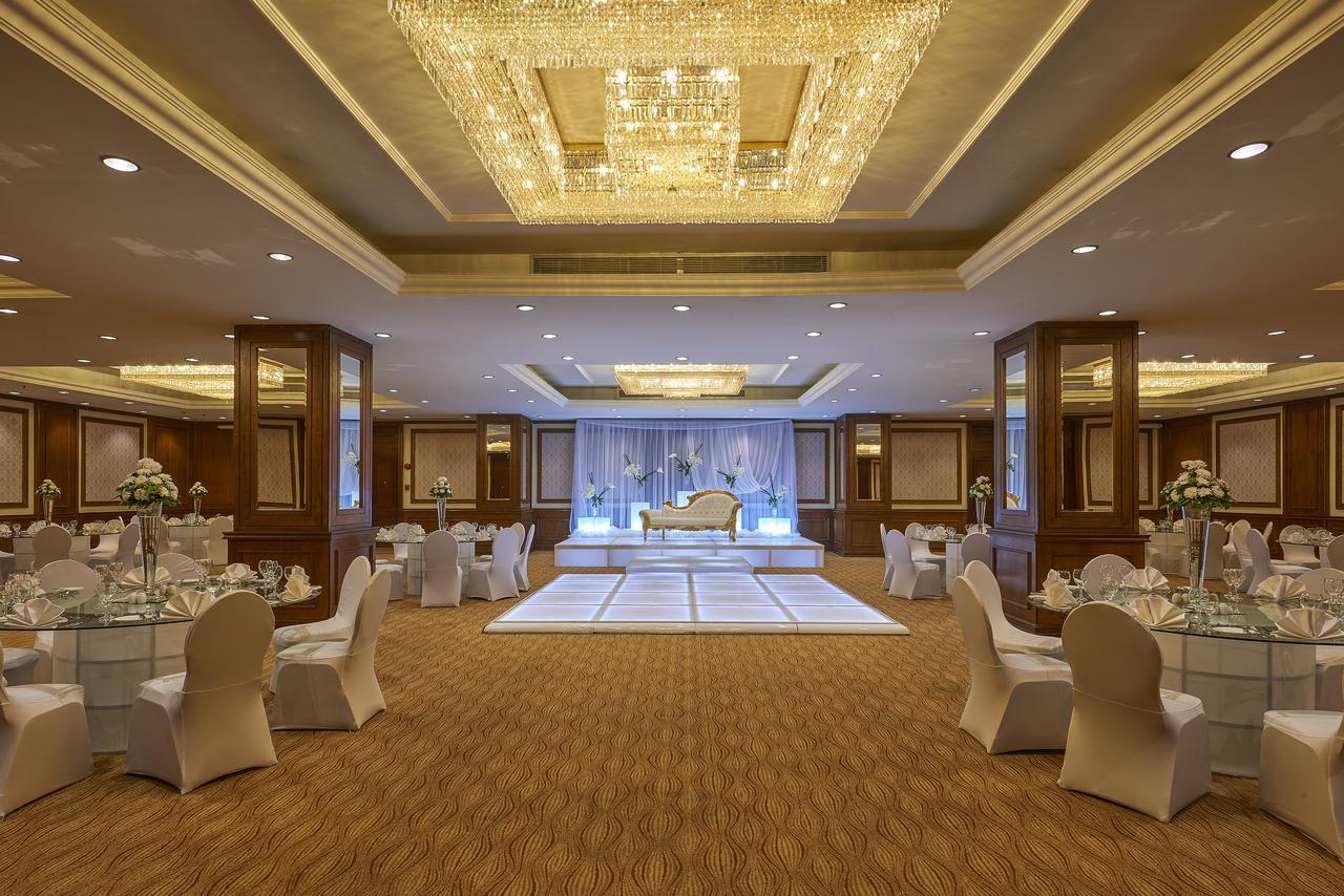 Safir Hotel Cairo Giza Ngoại thất bức ảnh The photo shows an elegantly decorated event space. The room features a beautiful chandelier hanging from the ceiling, providing a warm glow. In the center, there is a raised platform that appears to be set up for a ceremony or celebration. Surroundi
