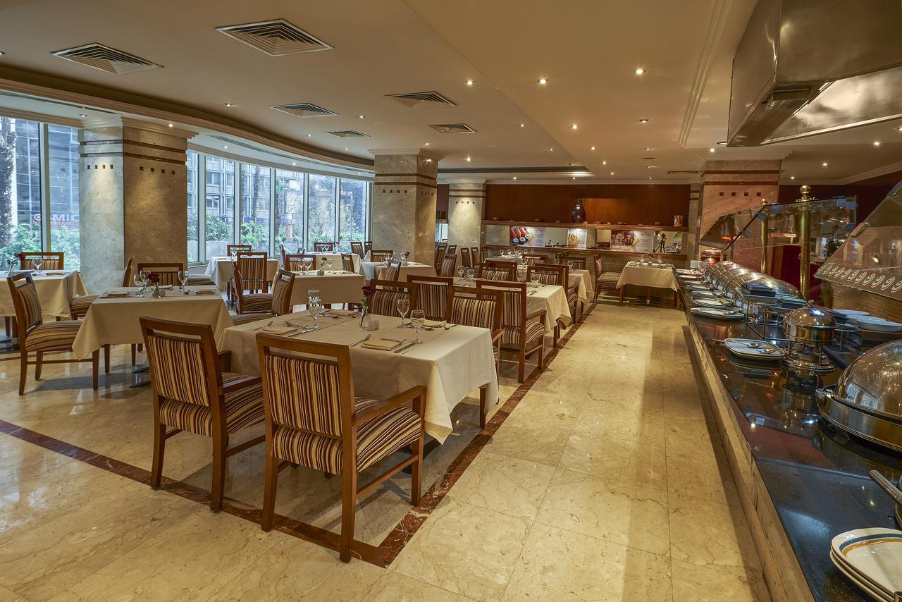 Safir Hotel Cairo Giza Ngoại thất bức ảnh The photo shows the interior of a restaurant. It features a spacious dining area with several tables laid out with white tablecloths. The tables are accompanied by wooden chairs that have striped patterns. The restaurant is well-lit with soft lightin
