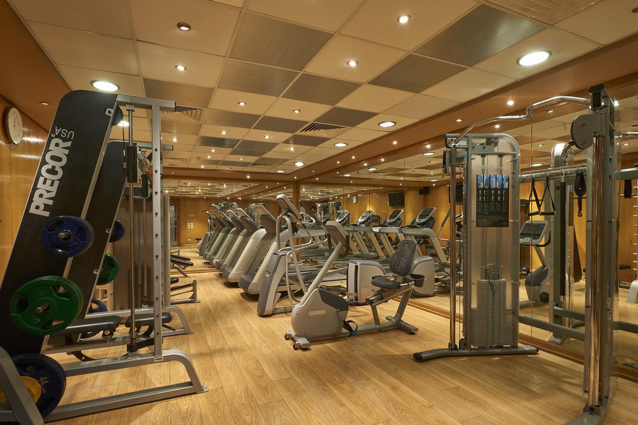 Safir Hotel Cairo Giza Ngoại thất bức ảnh The photo shows a well-equipped gym with various exercise machines. There are several cardio machines lined up, including treadmills, stationary bikes, and elliptical trainers. Strength training equipment is also present, including a multi-functional