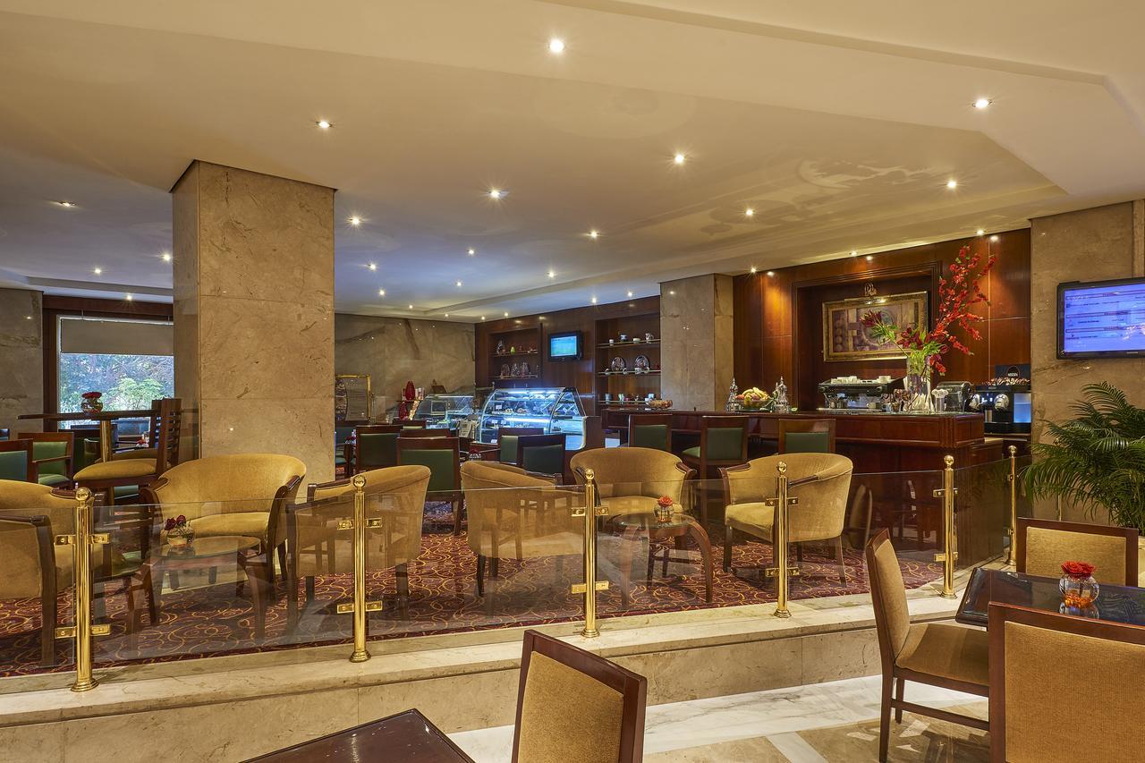 Safir Hotel Cairo Giza Ngoại thất bức ảnh The photo shows the interior of a café or restaurant. It features a well-lit space with modern decor, including comfortable seating arranged around small tables. There are elegant, plush chairs and a section that appears to be a counter or bar area, 